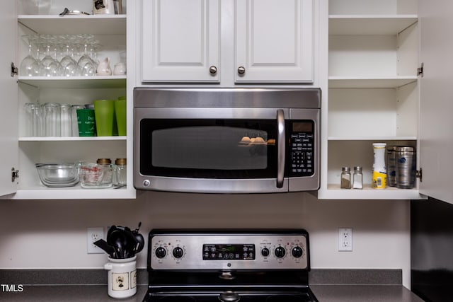 kitchen with white cabinetry, open shelves, dark countertops, and stainless steel appliances