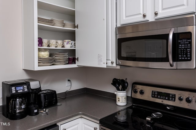 kitchen featuring dark countertops, white cabinetry, stainless steel appliances, and open shelves