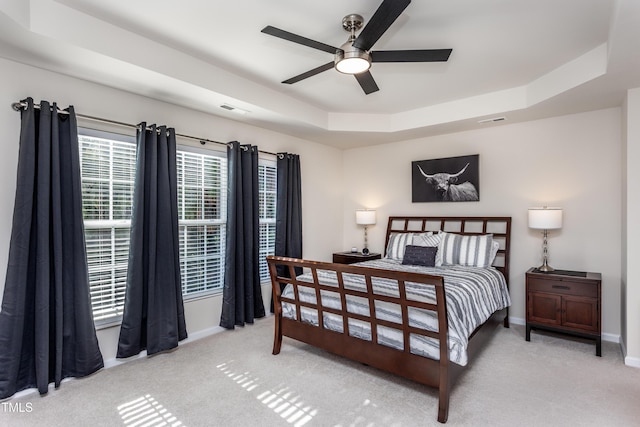 bedroom with a raised ceiling, carpet flooring, baseboards, and visible vents