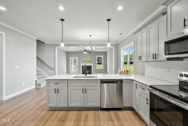 kitchen featuring stainless steel appliances, a peninsula, a sink, and gray cabinetry