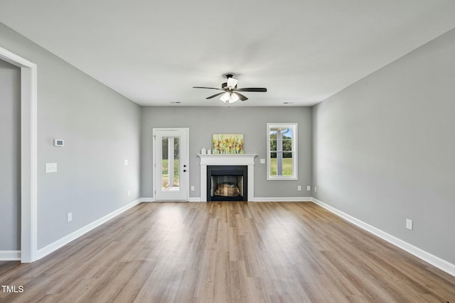 unfurnished living room featuring a fireplace, baseboards, and wood finished floors