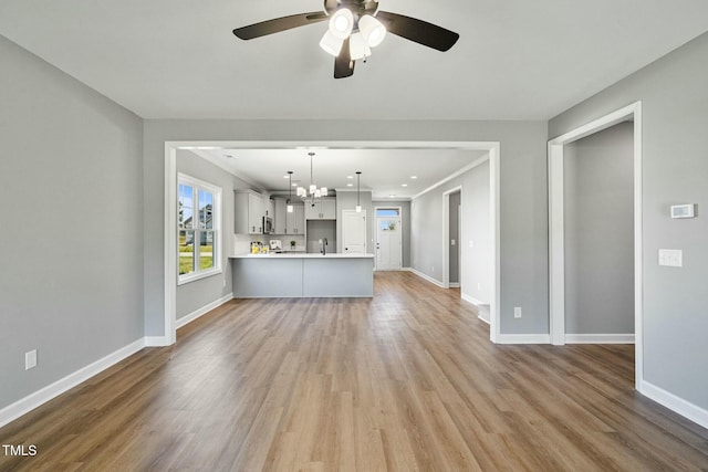 unfurnished living room featuring light wood-style floors, baseboards, and a sink