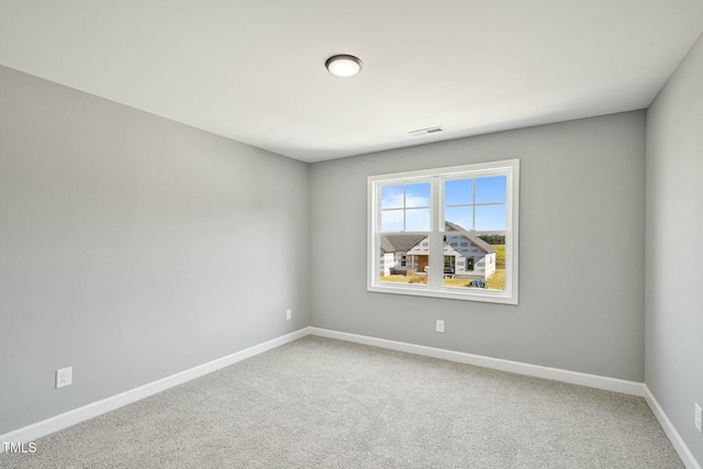 empty room featuring carpet, visible vents, and baseboards