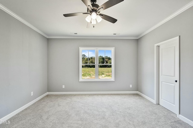 carpeted spare room featuring baseboards, ceiling fan, visible vents, and crown molding