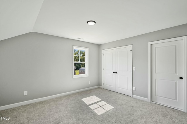 unfurnished bedroom featuring carpet flooring, vaulted ceiling, visible vents, and baseboards