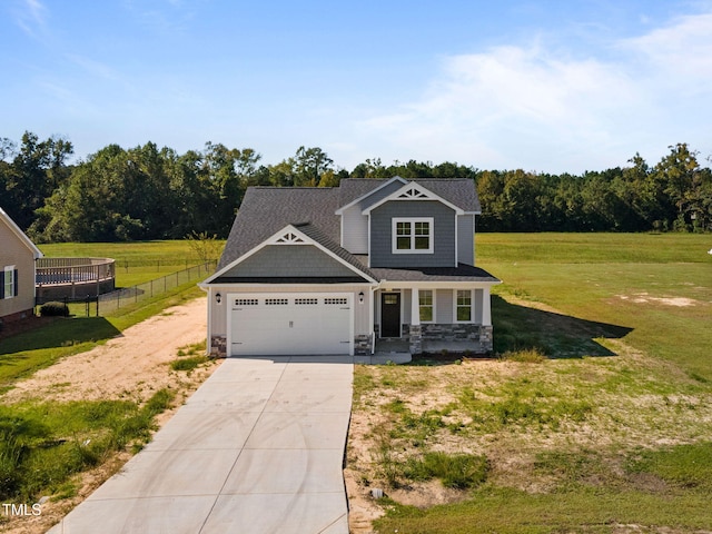 craftsman house with a garage, concrete driveway, stone siding, fence, and a front yard