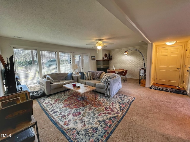 carpeted living room with visible vents, brick wall, a textured ceiling, and a ceiling fan