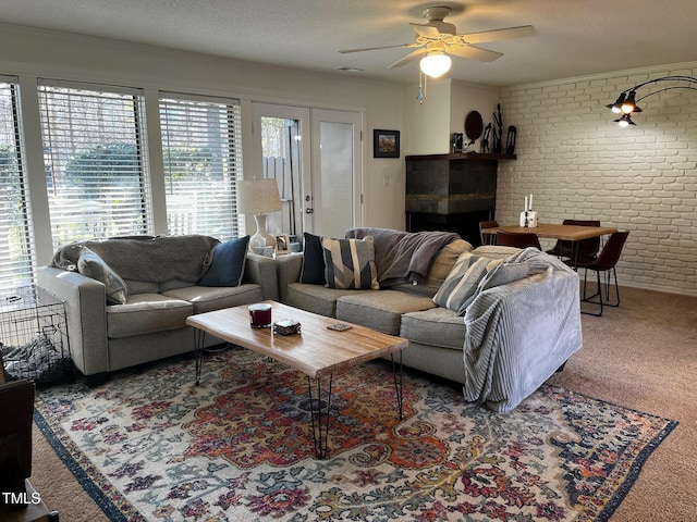 living area featuring ceiling fan, carpet floors, a textured ceiling, and brick wall