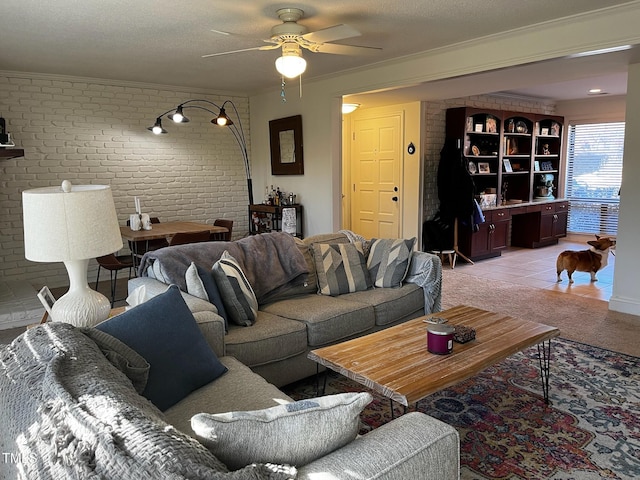 living room with a ceiling fan, light colored carpet, brick wall, and a textured ceiling