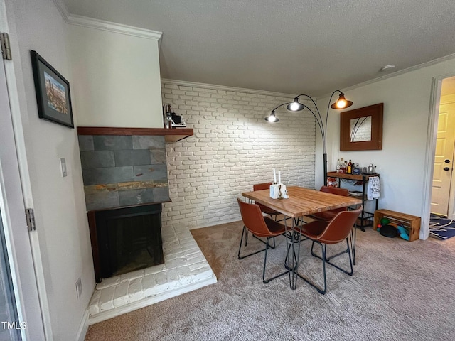 carpeted dining room with a fireplace with raised hearth, a textured ceiling, crown molding, and baseboards