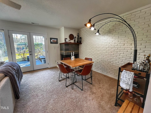 carpeted dining area featuring visible vents, brick wall, crown molding, french doors, and a textured ceiling