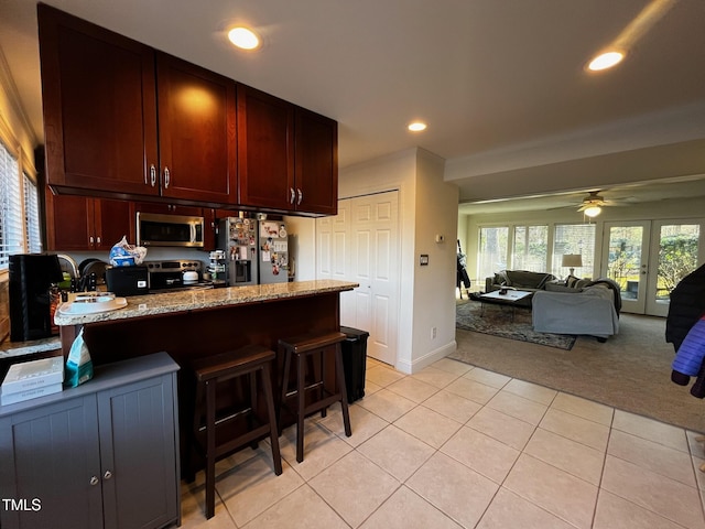 kitchen with light carpet, stainless steel appliances, a peninsula, a breakfast bar area, and light tile patterned floors