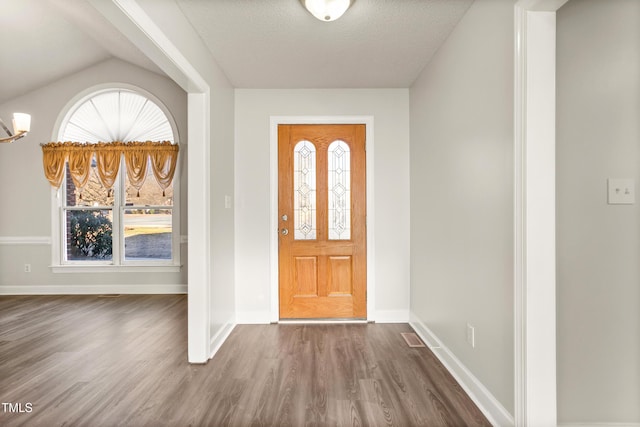 foyer entrance with visible vents, a textured ceiling, baseboards, and wood finished floors