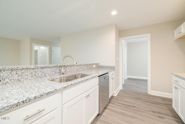 kitchen featuring light wood finished floors, a sink, light stone countertops, white cabinetry, and stainless steel dishwasher