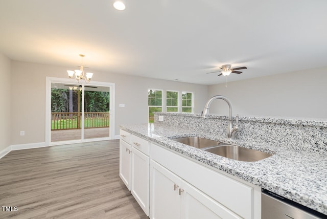 kitchen with a sink, white cabinets, light wood-type flooring, dishwasher, and pendant lighting