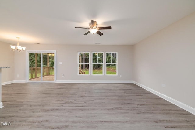 empty room featuring a healthy amount of sunlight, baseboards, and ceiling fan with notable chandelier