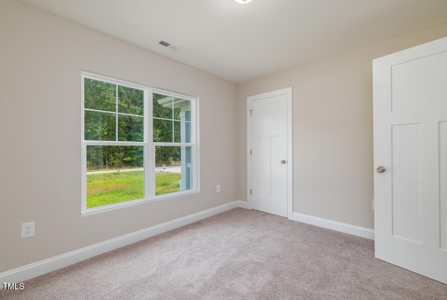 carpeted empty room featuring visible vents and baseboards