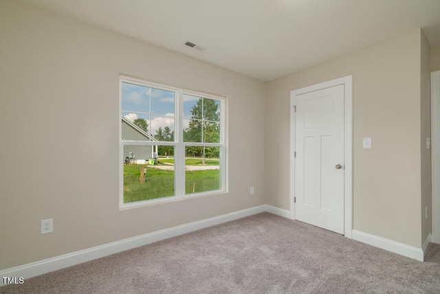 spare room with carpet flooring, visible vents, and baseboards