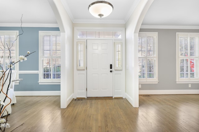 foyer entrance featuring arched walkways, plenty of natural light, and crown molding