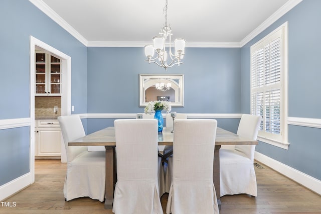 dining room with light wood-type flooring, a chandelier, and ornamental molding