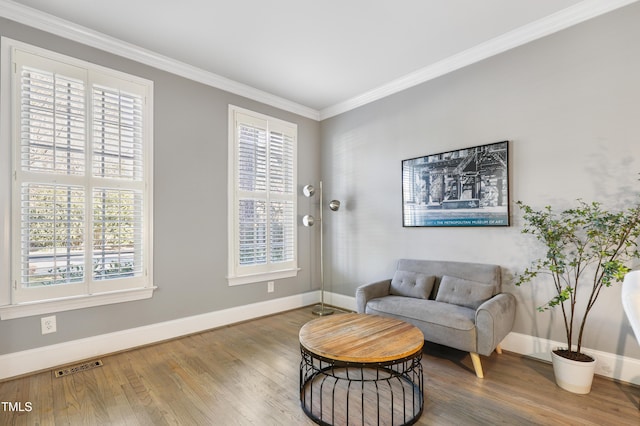 living area with baseboards, visible vents, wood finished floors, and ornamental molding