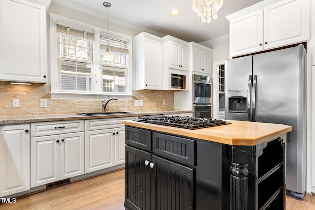 kitchen with stainless steel appliances, a sink, wood counters, white cabinetry, and crown molding