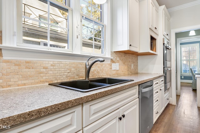 kitchen featuring a sink, white cabinets, ornamental molding, appliances with stainless steel finishes, and backsplash