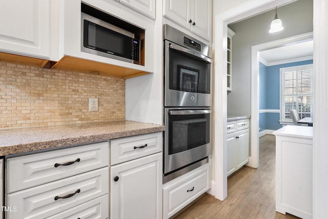 kitchen with appliances with stainless steel finishes, white cabinetry, crown molding, and decorative backsplash