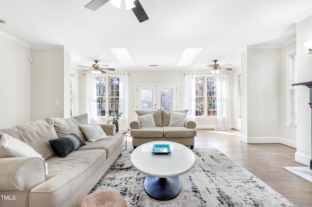 living area with ornamental molding, a skylight, plenty of natural light, and wood finished floors