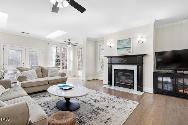 living area featuring ornamental molding, a premium fireplace, wood finished floors, and baseboards