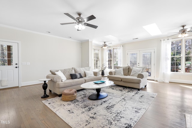 living room featuring plenty of natural light, a skylight, crown molding, and wood finished floors