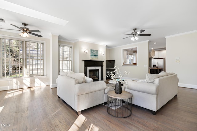 living room with baseboards, visible vents, wood finished floors, crown molding, and a fireplace