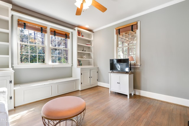 living area featuring ornamental molding, light wood-type flooring, plenty of natural light, and baseboards