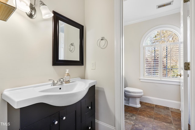 bathroom with baseboards, visible vents, toilet, ornamental molding, and vanity