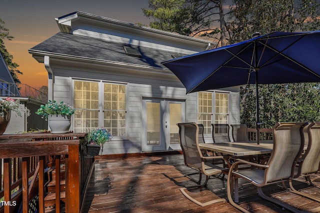 deck at dusk with outdoor dining space and french doors