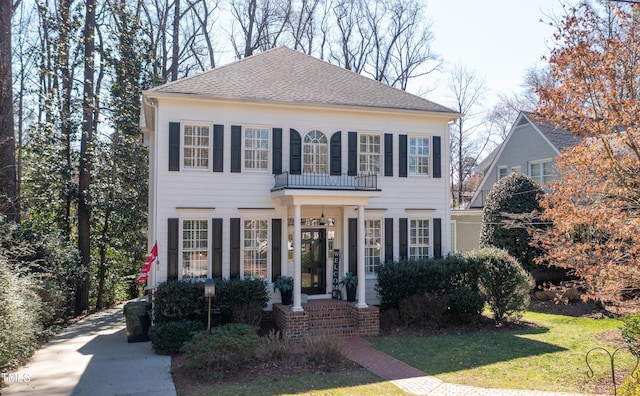 colonial house with a front lawn and a shingled roof