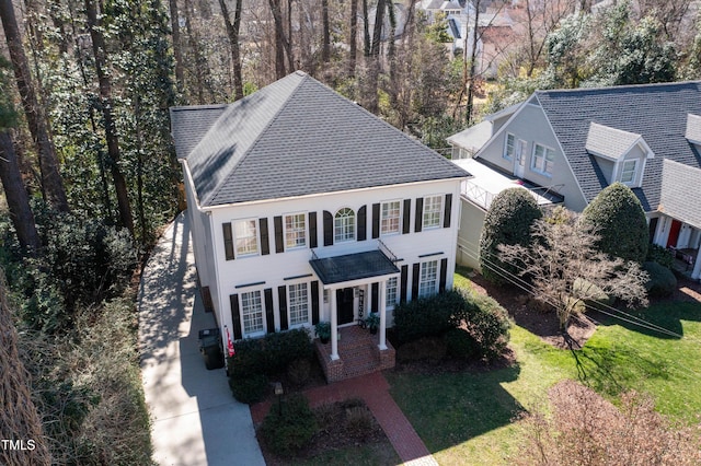 view of front of house with roof with shingles and a front lawn