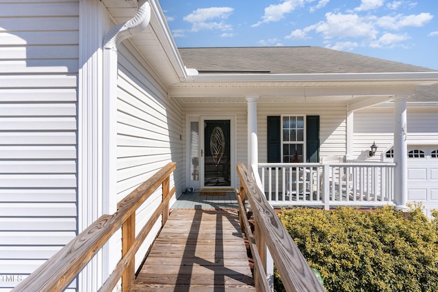 property entrance featuring covered porch, roof with shingles, and an attached garage