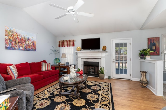 living area featuring baseboards, lofted ceiling, ceiling fan, wood finished floors, and a fireplace