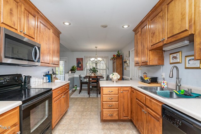 kitchen with brown cabinets, a sink, a peninsula, and black appliances