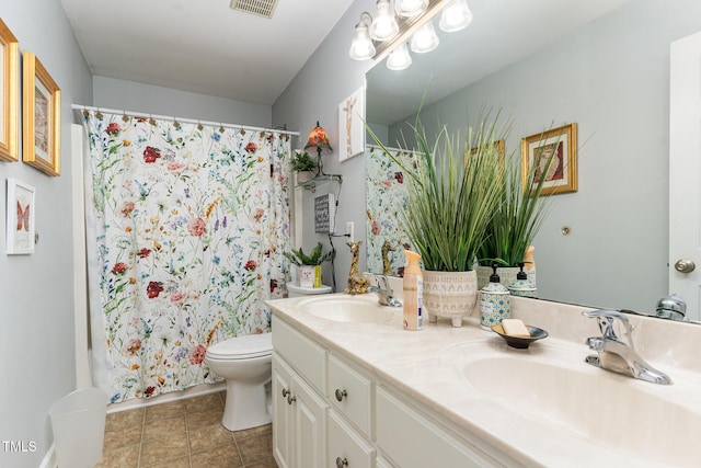 bathroom featuring visible vents, double vanity, a sink, and toilet