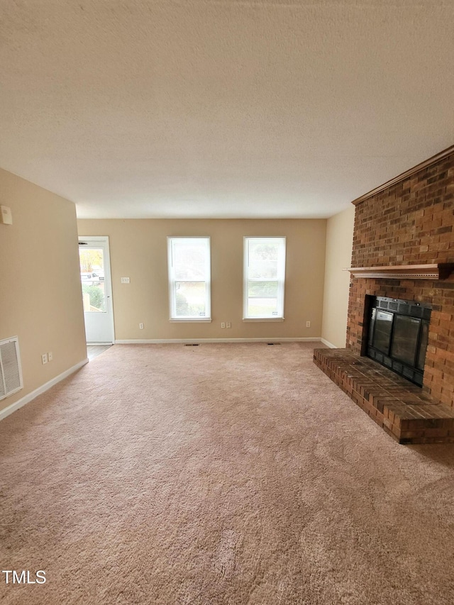 unfurnished living room featuring carpet, a healthy amount of sunlight, visible vents, and a fireplace