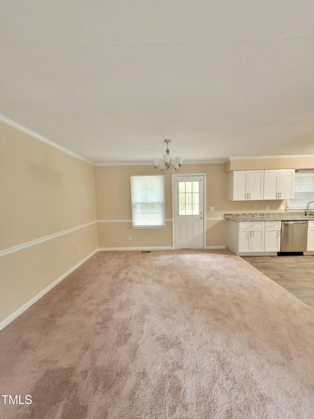 unfurnished living room featuring an inviting chandelier, baseboards, crown molding, and light colored carpet