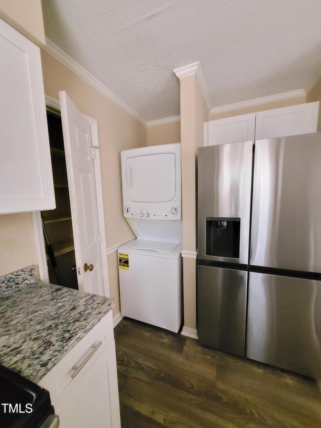 laundry area featuring dark wood-style flooring, stacked washer and dryer, ornamental molding, a textured ceiling, and laundry area