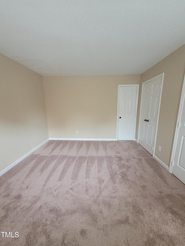 carpeted spare room featuring a textured ceiling and baseboards