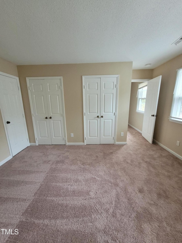 unfurnished bedroom featuring carpet, visible vents, and baseboards