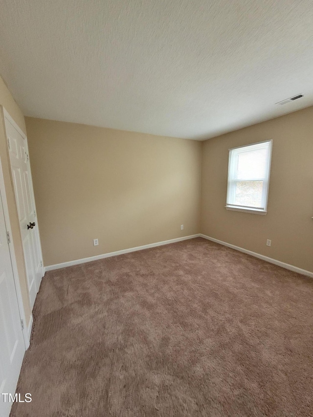 interior space with a textured ceiling, carpet, visible vents, and baseboards