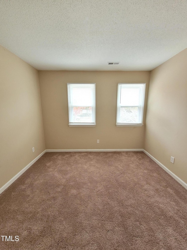 spare room with visible vents, plenty of natural light, and a textured ceiling