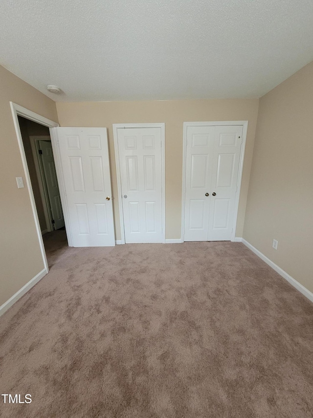 unfurnished bedroom with a textured ceiling, baseboards, and carpet flooring