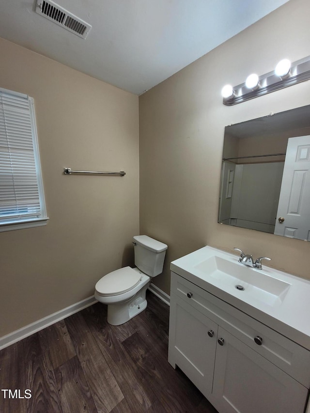 bathroom featuring toilet, baseboards, visible vents, and wood finished floors